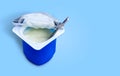 Yogurt, plastic cups and spoon on blue background. Yogurt made from milk fermented by added bacteria, often sweetened and flavored