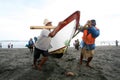 The fishermen are working together to lift and push the boats to shore