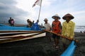 The fishermen are working together to lift and push the boats to shore