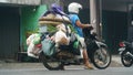 A woman is carrying a lot of merchandise on a motorbike