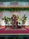 Just married muslim couple wearing traditional Javanese dress smiling to camera giving two thumbs up on wedding reception