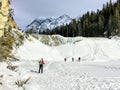 A group of hikers walking towards the frozen Wapta Falls with the Rocky Mountains in the background, in Yoho National Park Royalty Free Stock Photo