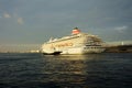 Sun rays break through storm clouds in the evening sky. Largest cruise ship in Japan Asuka II at