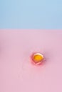 Yolk of broken egg in eggshell decorated with pink sisal nest on