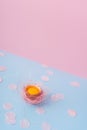 Yolk of broken egg in eggshell decorated with pink sisal nest an