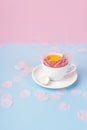 Yolk of broken egg in the shell in white coffee cup on a saucer, and blue chicken and quail eggs decorated with a pink sisal and