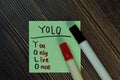 YOLO - You Only Live Once write on sticky notes isolated on Wooden Table