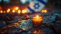 Yom HaZikaron theme, a single candle lit in a small glass, placed on a stone surface with the backdrop of a waving