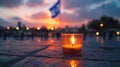 Yom HaZikaron theme, a single candle lit in a small glass, placed on a stone surface with the backdrop of a waving