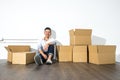 A yong asian man sitting on floor smiling with boxes