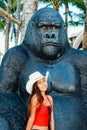 Yong beautiful Asian girl sitting on the giant monkey statue