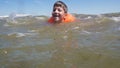 Boy in lifejacket swim in sea with waves