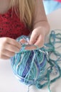 Yong girl learning to crochet with multicoloured wool yarn. Homemade handiwork can be a nice and creative present