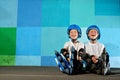Yong little athletic boys on roller sitting against the blue graffiti wall