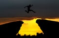 yong man jump over city scaoe and through on the gap of hill silhouette evening colorful sky. Royalty Free Stock Photo
