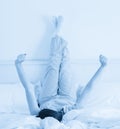 Yong woman in bed with legs up high against wall Royalty Free Stock Photo