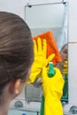 Yong woman cleaning the mirror with rag and spray Royalty Free Stock Photo