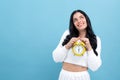 Yong woman holding a clock showing 6AM Royalty Free Stock Photo