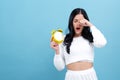 Yong woman holding a clock showing 6AM Royalty Free Stock Photo