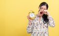 Yong woman holding a clock showing 6AM Royalty Free Stock Photo