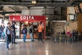 People customers at Costa Coffee stand in railway station with seating area
