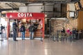 People customers at Costa Coffee stand in railway station with seating area