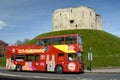 York sightseeing tour bus waits by Cliffords's tower a stone monument in York UK