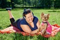 Yorkshire terrier with fat female owner on picnic on sunny summer day.