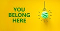 You belong here symbol. Green shining light bulb icon. Words You belong here. Beautiful yellow background. Diversity, inclusion,