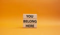 You belong here symbol. Wooden blocks with words You belong here. Beautiful orange background. Business and You belong here