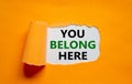 You belong here symbol. Words `You belong here` appearing behind torn orange paper. Beautiful orange background. Business,