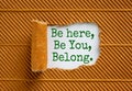 You belong here symbol. Words Be here, be you, belong appearing behind torn black paper. Beautiful brown background. Business,