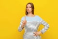 You better not. Young serious woman shaking finger scolding gesture, warning, prohibit smth, saying no, standing over yellow