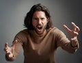 You better run. Studio shot of a young man screaming in anger against a gray background. Royalty Free Stock Photo