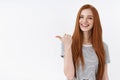 You better see it. Charming lively happy smiling redhead girl blue eyes pointing thumb left giving direction showing Royalty Free Stock Photo