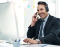 When you call, we answer. a mature businessman using a headset while working on a computer in an office. Royalty Free Stock Photo