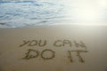 You can do it. Motivational inspirational message concept written on the sand of beach.