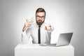 You can earn money! Portrait of handsome satisfied bearded young boss in white shirt and black tie sitting in office, pointing to Royalty Free Stock Photo