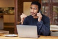 You can meet me at the cafe and we can discuss it. a man talking on his cellphone and using his laptop while sitting in Royalty Free Stock Photo