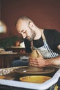 You can shape your life into whatever you want. a young man working with clay in a pottery studio.