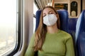 You can sleep peacefully. Relaxed beautiful woman with medical face mask sleeping sitting in the train. Train passenger traveling Royalty Free Stock Photo