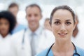 You can trust this team of experts. Happy female doctor smiling at the camera with her colleagues in the background. Royalty Free Stock Photo