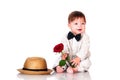 Smiling one old year boy in retro, bow-tie hat and with red rose sitting on white background. Royalty Free Stock Photo