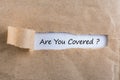 ARE YOU COVERED Question message appearing behind ripped brown paper. Are you insured for your car, travel, home, health