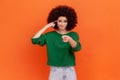 You are crazy. Attractive woman with Afro hairstyle wearing green sweater holding finger near temple Royalty Free Stock Photo