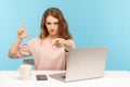 You are fired! Angry woman boss sitting at workplace and showing loser gesture, pointing to camera, blaming for unsuccess