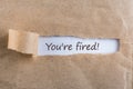 You are fired. Message in letter or note, appearing behind ripped brown paper of envelope text you are fired Royalty Free Stock Photo