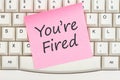 You are fired message on a pink sticky note on a gray computer keyboard Royalty Free Stock Photo
