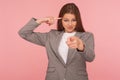 You are insane, out of mind! Portrait of young woman in business suit showing stupid gesture and pointing to camera