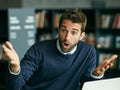 Are you kidding me Its brilliant. a handsome young businessman sitting in a library alone and looking shocked while Royalty Free Stock Photo